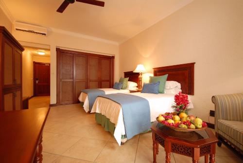 a hotel room with two beds and a bowl of fruit at Avani Pemba Beach Hotel in Pemba