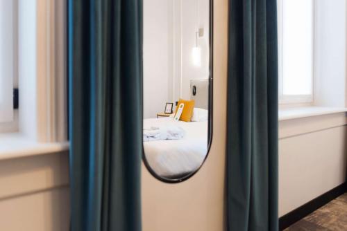 a mirror reflection of a bed in a room at Best Western Urban Hotel in Lille