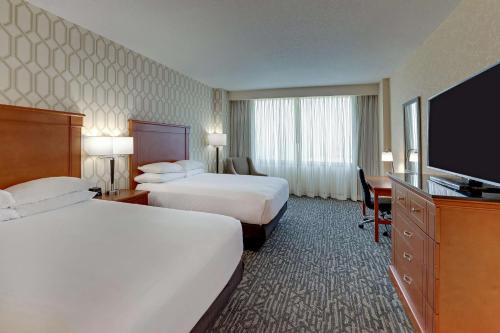 a hotel room with two beds and a flat screen tv at Drury Plaza Hotel Nashville Franklin in Franklin