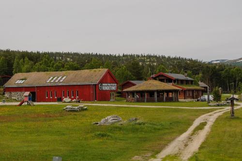 a red barn in a field next to a dirt road at Rondane Friluftssenter Rondetunet in Brenn