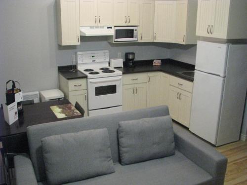 a kitchen with white appliances and a gray couch at Le Citadin in Rouyn