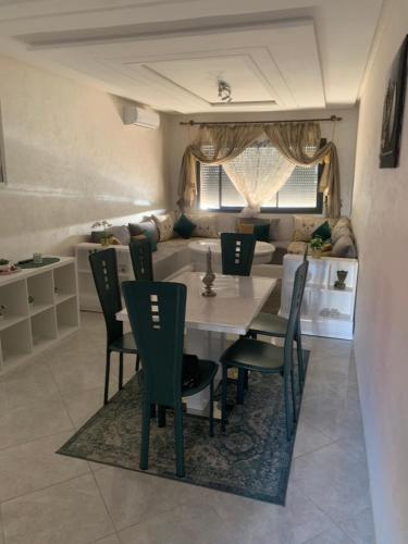 a dining room with a table and chairs and a couch at Appartement avec piscine et proch de plage in Kenitra