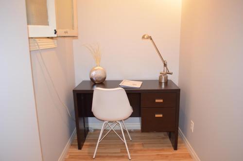 a desk with a white chair and a lamp at Le Citadin in Rouyn