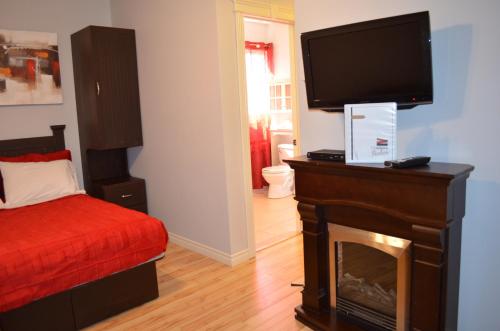 a bedroom with a fireplace and a flat screen tv at Le Citadin in Rouyn