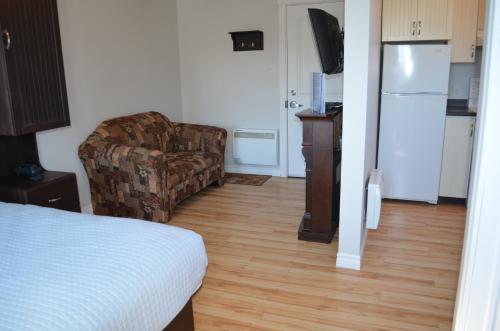 a room with a bed and a couch and a kitchen at Le Citadin in Rouyn