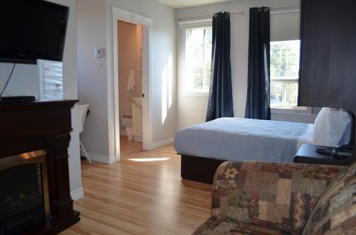 a bedroom with a bed and a couch and a television at Le Citadin in Rouyn-Noranda