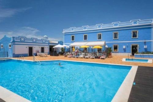 a large swimming pool in front of a blue building at Lovely 2 Bedroom Home inside a Resort in Albufeira in Albufeira