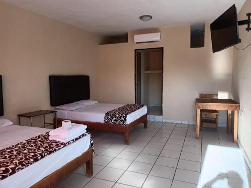 a hotel room with two beds and a television at HOTEL MARIA TERESA in Río Verde