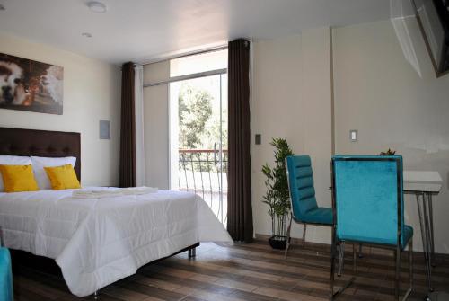 a bedroom with a bed and two blue chairs at Bon Repos Boutique in Arequipa