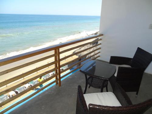 a balcony with chairs and a table and the ocean at Akas Hotel Apartamentos in Canoas De Punta Sal
