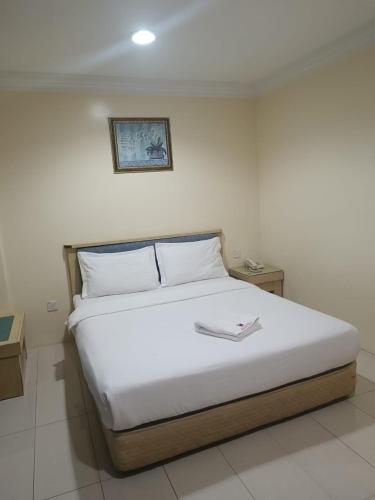 a bedroom with a white bed with a picture on the wall at HOTEL AMBASSADOR 2 in Labuan