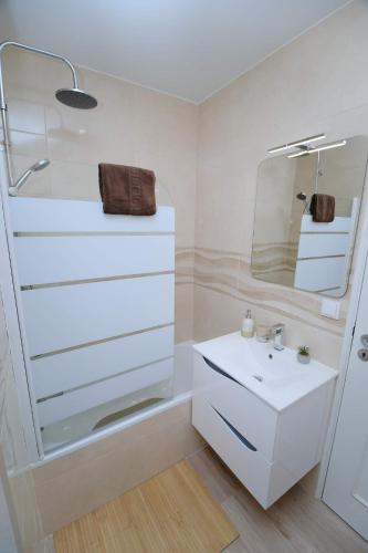 a white bathroom with a sink and a mirror at Diamante house com garagem privada in Braga