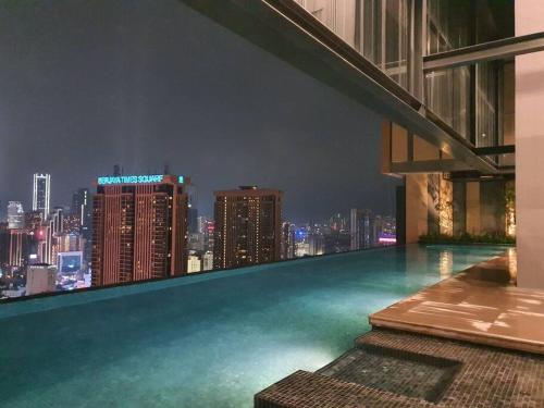 a rooftop swimming pool with a city skyline at night at Infinity pool/ Lucentia BBCC, near LALAPORT, PNB118, KLCC in Kuala Lumpur