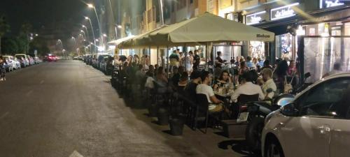 a group of people sitting at tables on a street at night at Salinas Mar y Playa in Roquetas de Mar