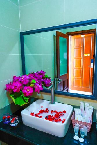 a bathroom sink with pink flowers and a mirror at Côn Sơn Victory Hotel in Con Dao