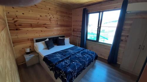ein Schlafzimmer mit einem Bett in einer Holzhütte in der Unterkunft Вила ВлаиДа in Saparewa Banja