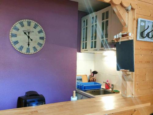 une cuisine avec une horloge sur un mur violet dans l'établissement Studio proche centre pour 2/4 personnes, cuisine équipée, près thermes et télécabines - FR-1-234-281, à Cauterets