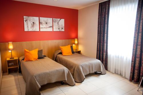 2 łóżka w pokoju z czerwonymi ścianami w obiekcie Hotel Pax w Luksemburgu