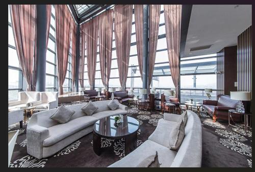 a large living room with couches and tables and windows at Shanghai Hongqiao Airport Hotel - Air China in Shanghai