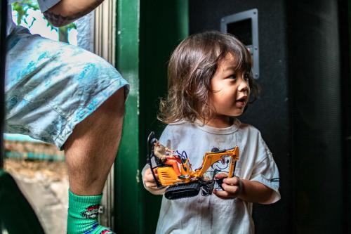 a little girl holding a toy truck in front of a man at HOSTEL CHILLAX in Osaka