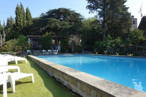 une grande piscine avec des chaises blanches et des arbres dans l'établissement Château Moussoulens, à Moussoulens