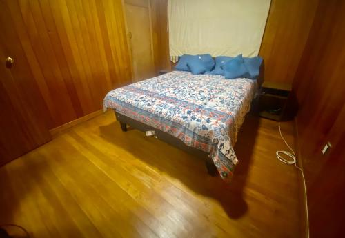 a bedroom with a bed with a blue comforter at Viva Chile Hostal - Puerto Varas in Puerto Varas
