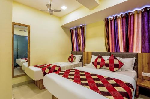 a bedroom with two beds and a mirror at Hotel BKC Corporate Inn in Mumbai