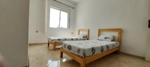 1 dormitorio con 2 camas y ventana en Villa CLIMATISEE avec piscine privée, ras el ma, en Tazagouin