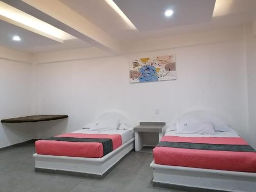 2 camas en una habitación con paredes blancas en Hotel San Carlos Yautepec, en Yautepec