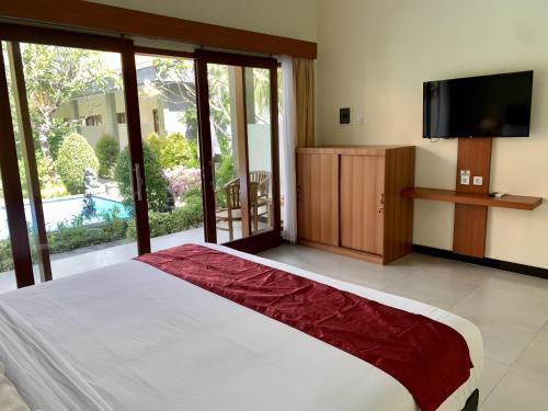 a bedroom with a large bed with a flat screen tv at Davit Guesthouse Nusa Dua in Nusa Dua