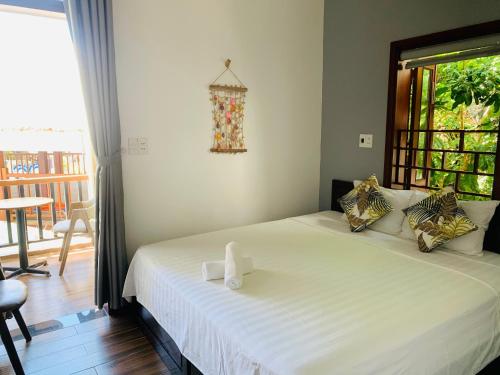 a bedroom with a white bed with a window and a table at Monkey Homestay & Bar in Tân Hiệp