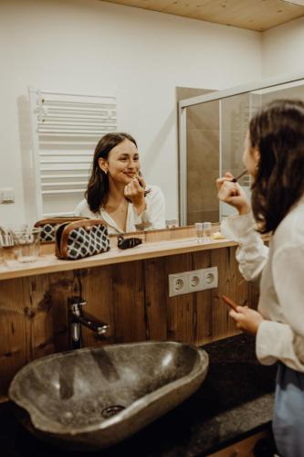 a woman brushing her teeth in front of a bathroom mirror at Herbst Wohnerlebnis in Lofer