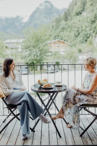 two women sitting at a table on a balcony at Herbst Wohnerlebnis in Lofer