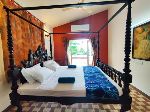 a bedroom with a canopy bed with red walls at Luxury 3-BHK Villa with infinity Pool in Old Goa