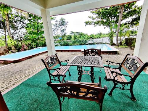 a patio with a table and chairs and a pool at Luxury 3-BHK Villa with infinity Pool in Old Goa