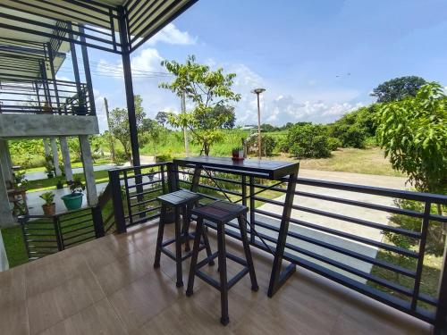a balcony with a table and two stools at บ้านแม่อุทัยธานี Baanmae Uthaithani in Uthai Thani