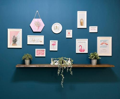 a shelf on a blue wall with pictures and plants at The Uniique Haus - Johor 1st Staycation Water Dining Experience in Johor Bahru