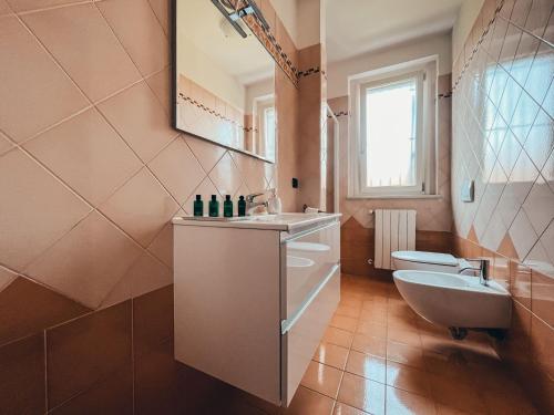 een badkamer met een wastafel, een toilet en een spiegel bij Appartamento Incantevole a 100metri dal mare e vicino a pista ciclabile in Imperia