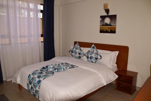 a bedroom with a bed with white sheets and blue pillows at Sai Inn Eldoret in Eldoret