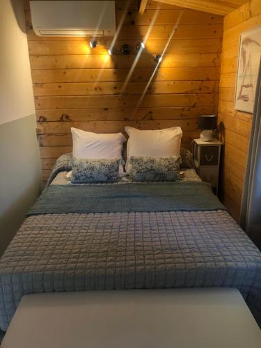 a bedroom with a bed with a wooden wall at Chalet - Piscine - Wifi in Penta-di-Casinca
