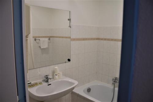 y baño con lavabo, espejo y bañera. en Adonis Cannes - Hôtel Thomas, en Le Cannet