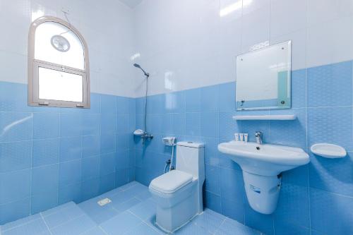 Baño azul con aseo y lavamanos en Super OYO 110 Ras Al Hadd Guest House en Al Ḩadd