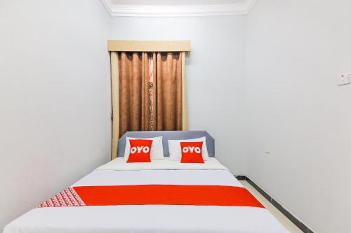 a bedroom with a bed with two red pillows at Super OYO 110 Ras Al Hadd Guest House in Al Ḩadd