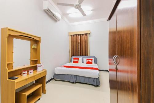 a bedroom with a bed and a desk and a mirror at Super OYO 110 Ras Al Hadd Guest House in Al Ḩadd