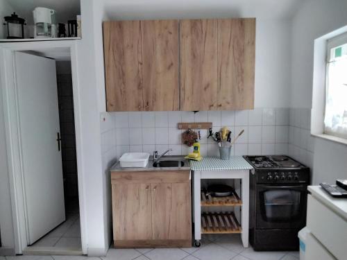 a kitchen with wooden cabinets and a sink and a stove at Apartmani Erceg in Jadrija