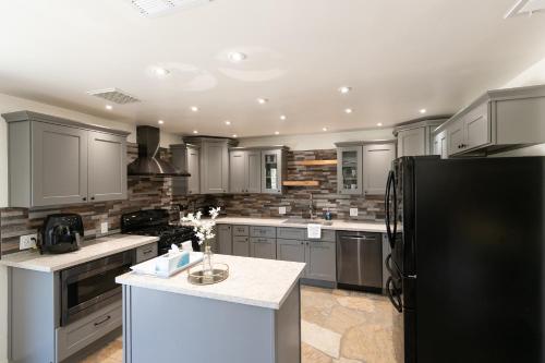 a kitchen with gray cabinets and a black refrigerator at Desert Ruby in Yucca Valley