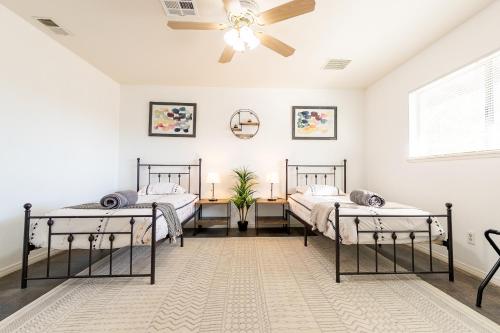 two beds in a room with a ceiling fan at Desert Ruby in Yucca Valley