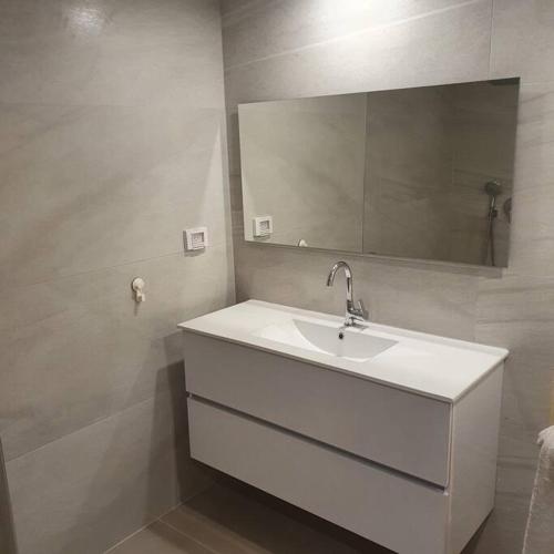 y baño con lavabo blanco y espejo. en יחידת דיור מושלמת בגבעה C במודיעין, en Modi'ín