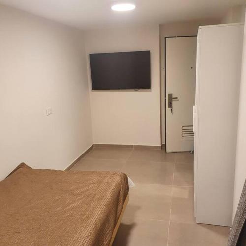 a bedroom with a bed and a flat screen tv at יחידת דיור מושלמת בגבעה C במודיעין in Modi'in-Maccabim-Re'ut