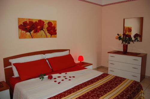 a bedroom with a bed with red pillows and a dresser at Albicocche House in Giarre